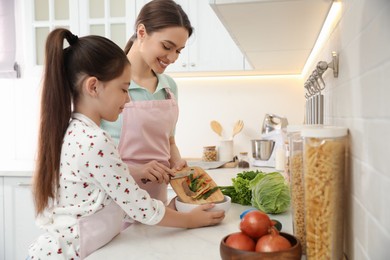 Photo of Mother and daughter peeling vegetables at kitchen counter