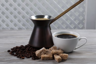 Photo of Hot turkish coffee pot, beans and sugar on white wooden table