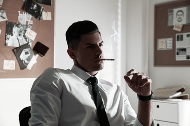 Professional detective smoking cigarette in his office