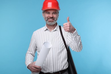 Architect in hard hat holding draft and showing thumb up on light blue background