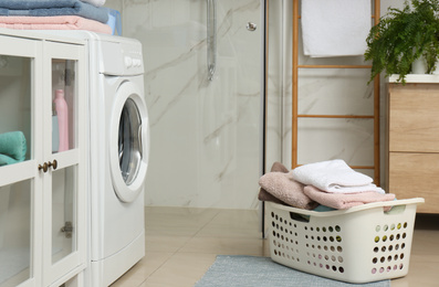 Basket with laundry and washing machine in bathroom