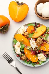 Photo of Delicious persimmon salad with cheese and pomegranate served on white table, flat lay