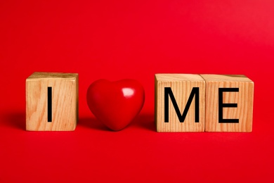 Phrase I Love Me made with wooden cubes and heart on red background