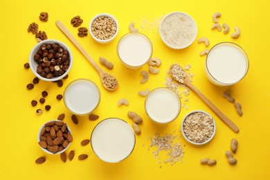 Photo of Different vegan milks and ingredients on yellow background, flat lay