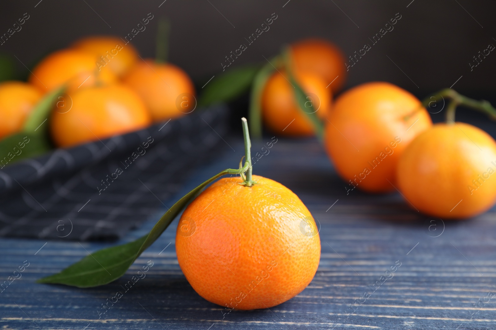 Photo of Fresh ripe tangerine on blue wooden table, closeup