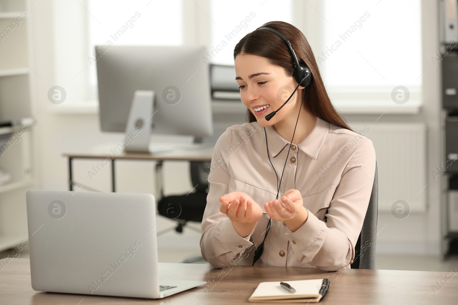 Photo of Hotline operator with headset working on laptop in office