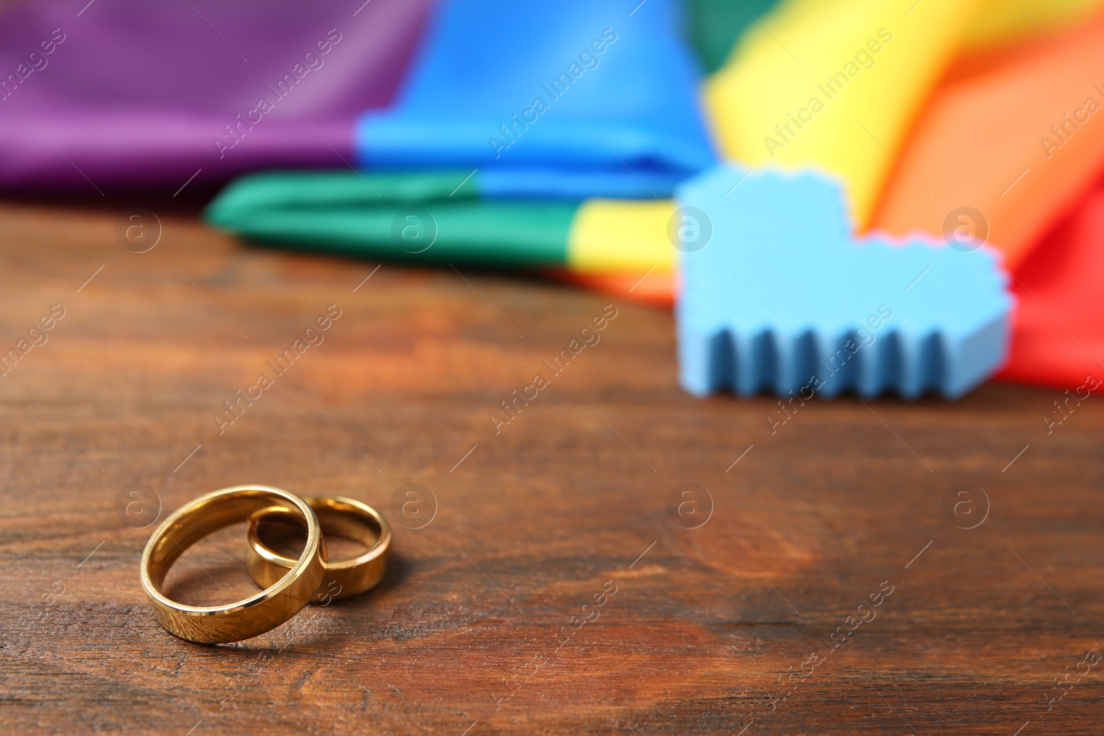 Photo of Wedding rings and rainbow flag on wooden table. Gay marriage