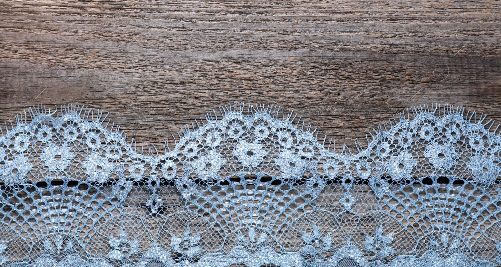 Photo of Beautiful lace on wooden table, top view. Space for text