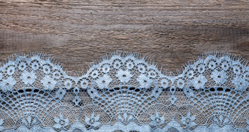 Photo of Beautiful lace on wooden table, top view. Space for text