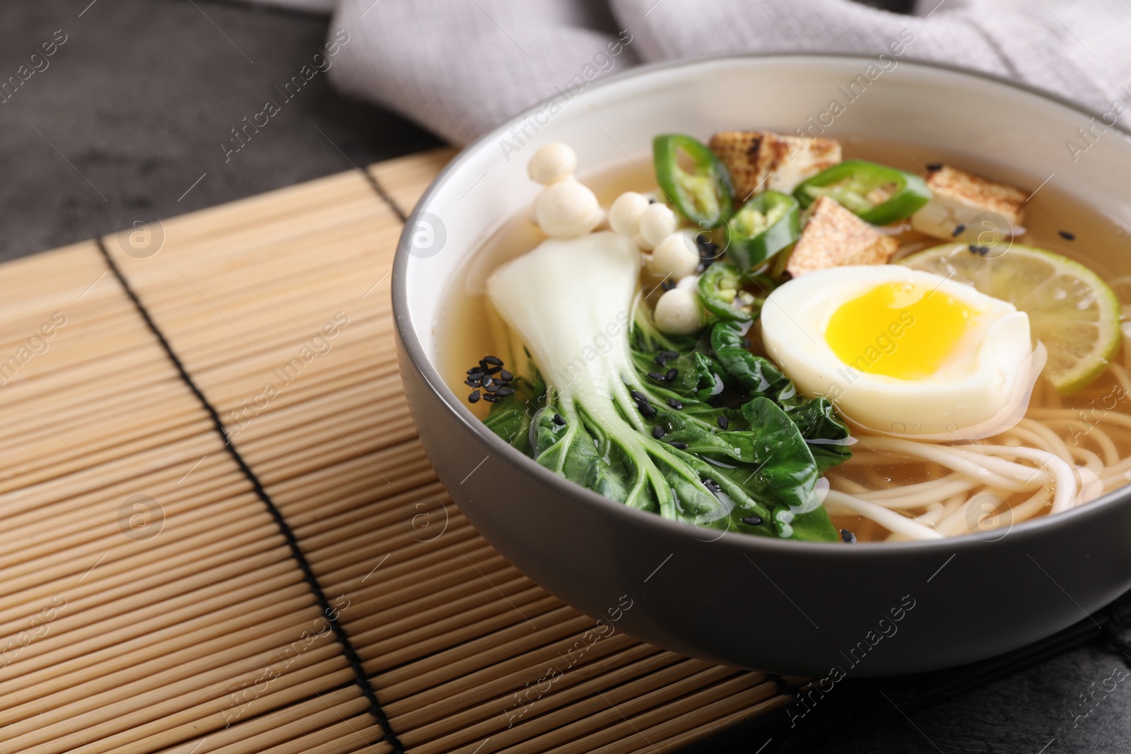 Photo of Bowl of vegetarian ramen on table, closeup. Space for text