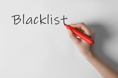 Image of Woman writing word Blacklist on whiteboard, closeup