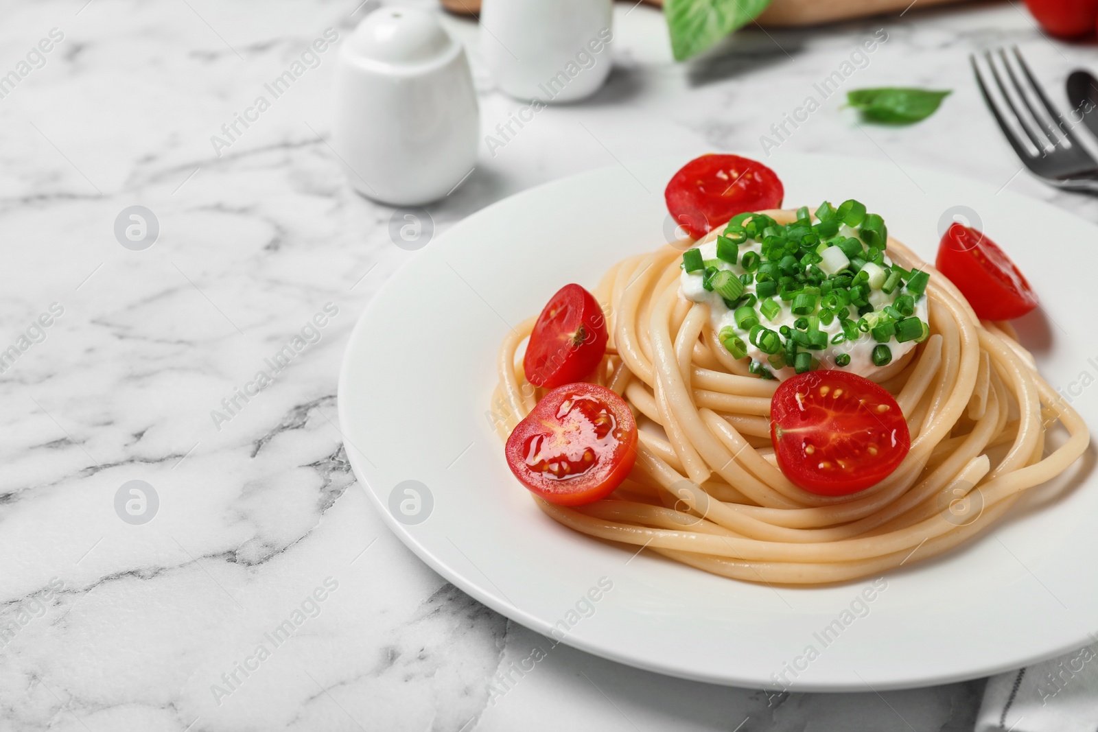 Photo of Delicious spaghetti with sour cream dressing on white marble table