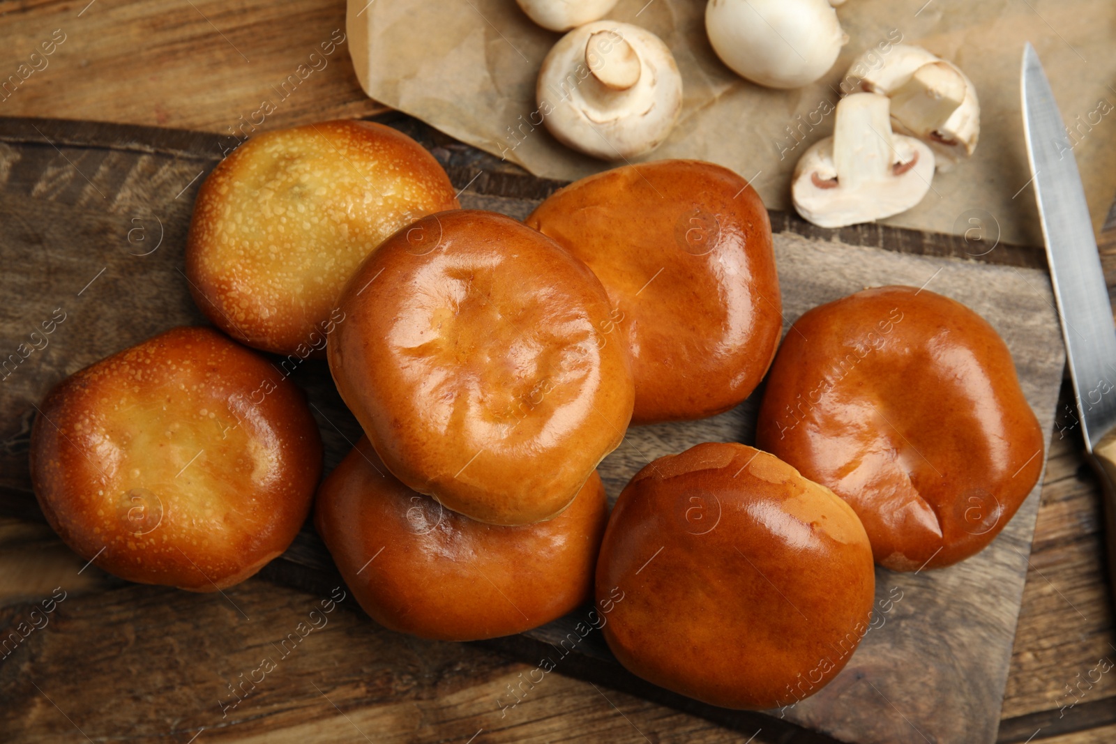 Photo of Delicious baked mushrooms pirozhki on wooden table