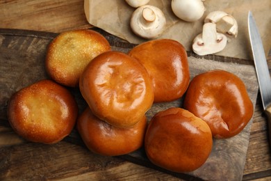 Photo of Delicious baked mushrooms pirozhki on wooden table