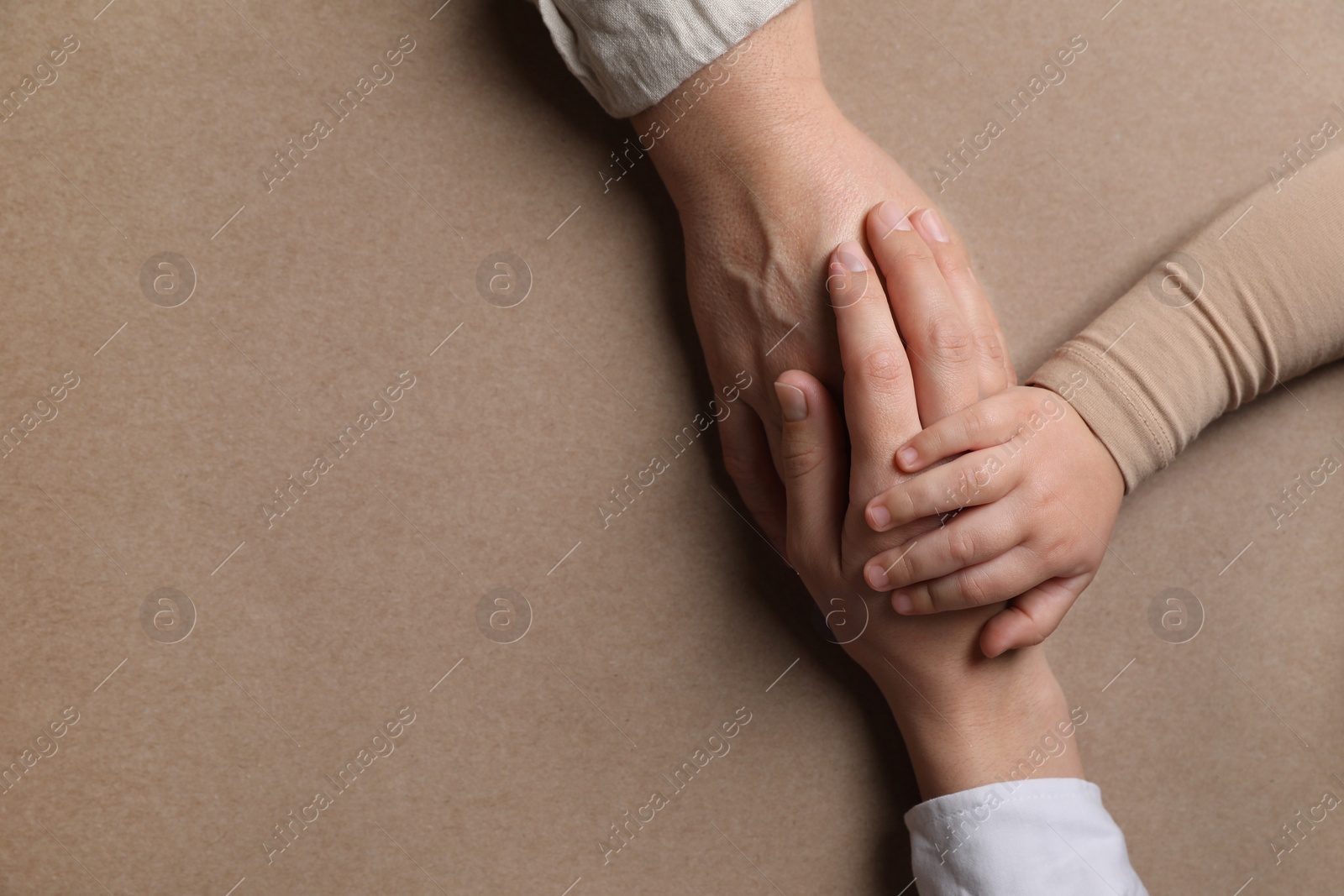 Photo of Family holding hands together on brown background, top view. Space for text