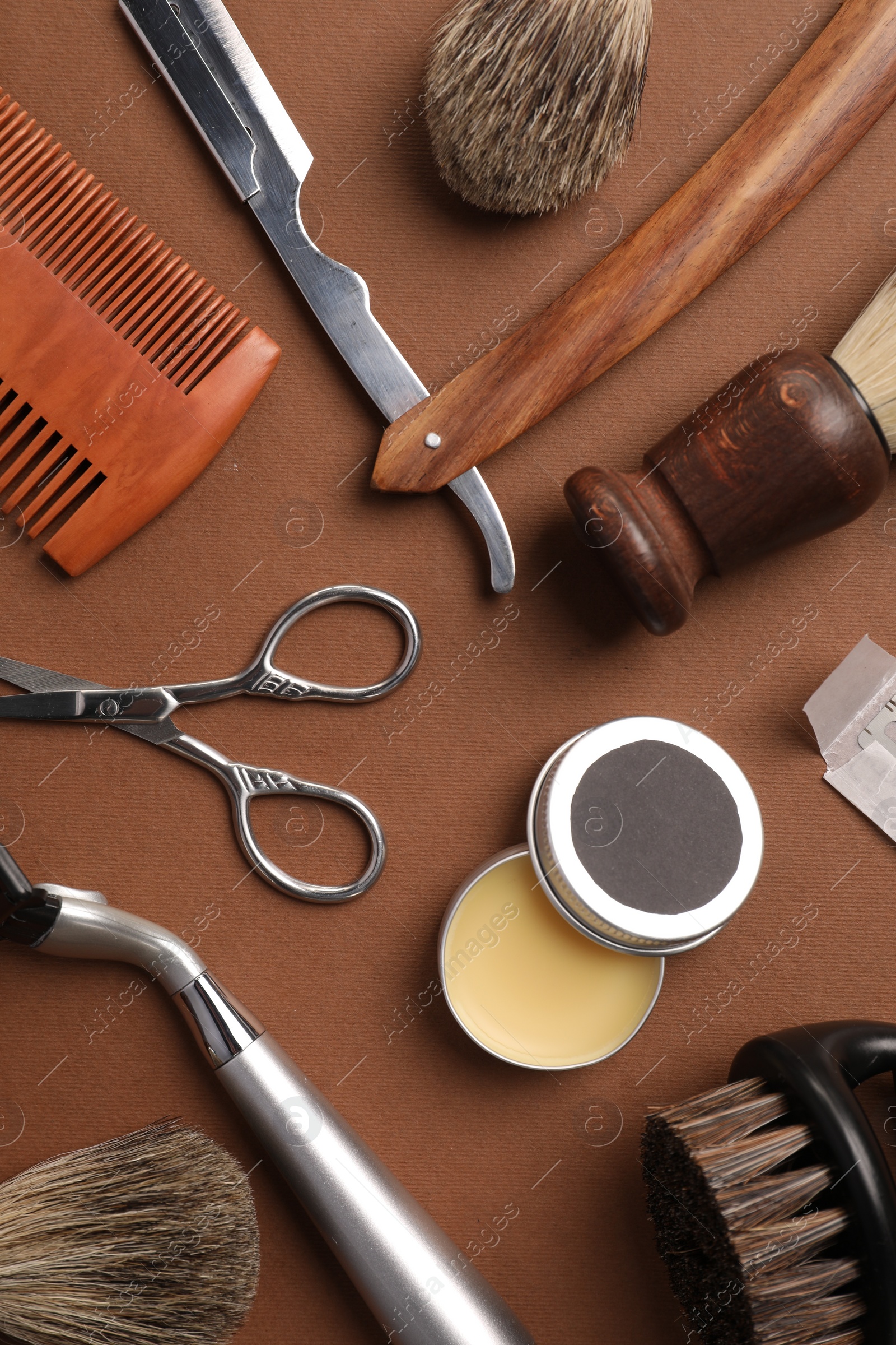 Photo of Moustache and beard styling tools on brown background, flat lay