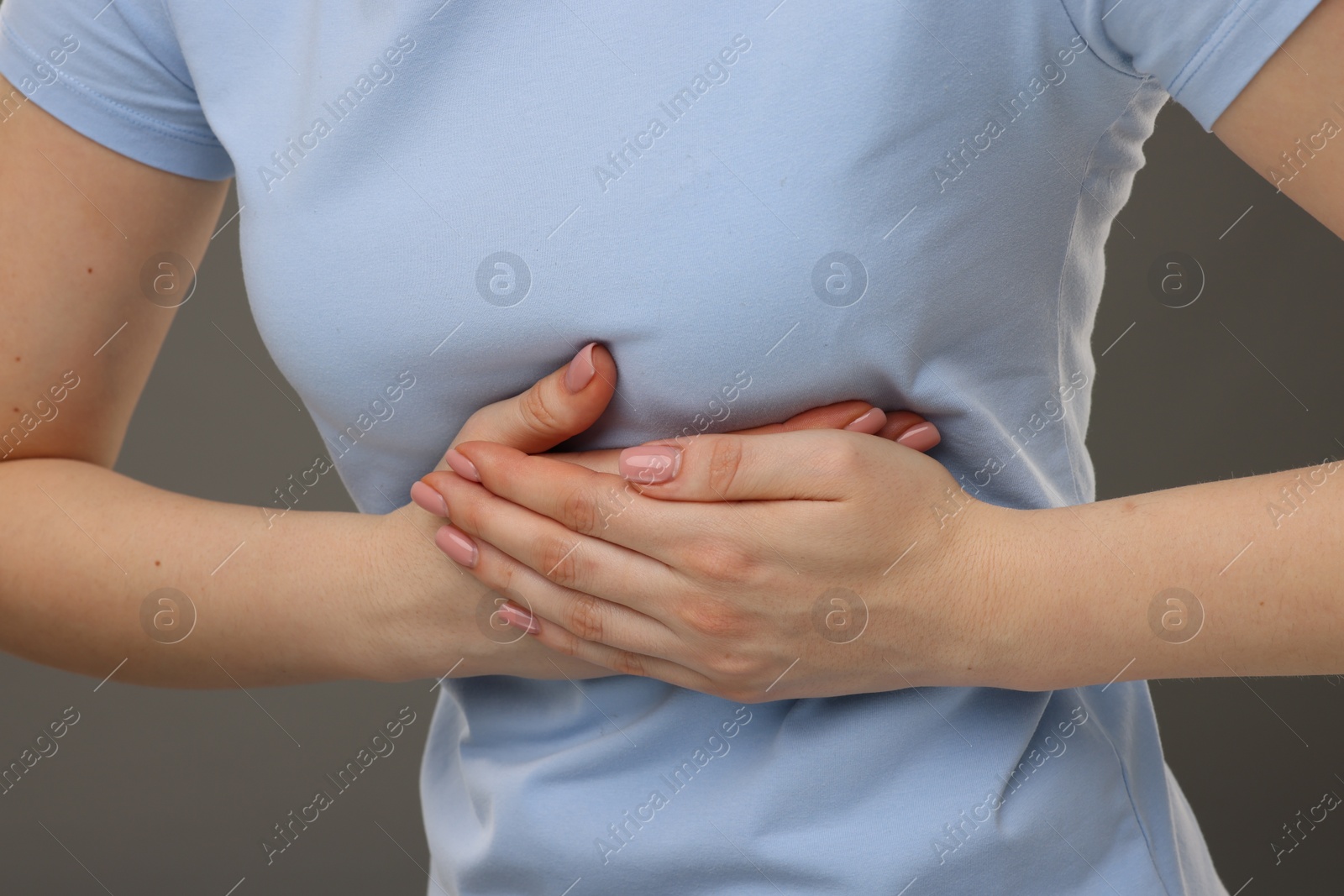 Photo of Woman having heart attack on grey background, closeup