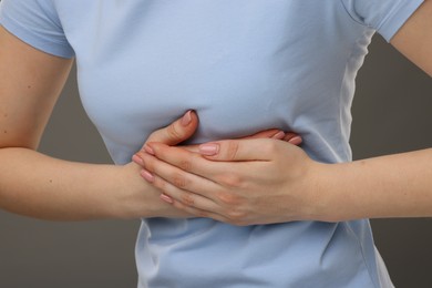 Photo of Woman having heart attack on grey background, closeup