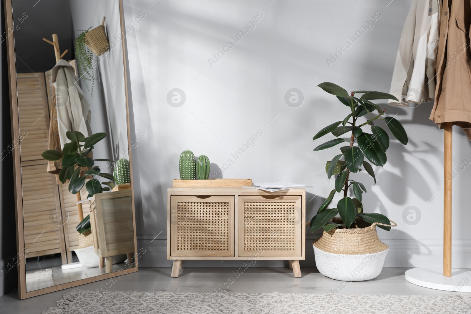 Photo of Stylish hallway room interior with wooden commode, coat rack and large mirror