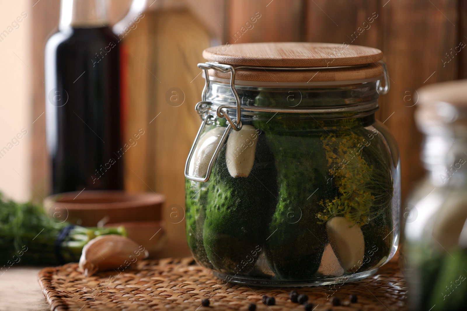 Photo of Glass jar with cucumbers, dill and garlic on wooden table. Canning vegetable