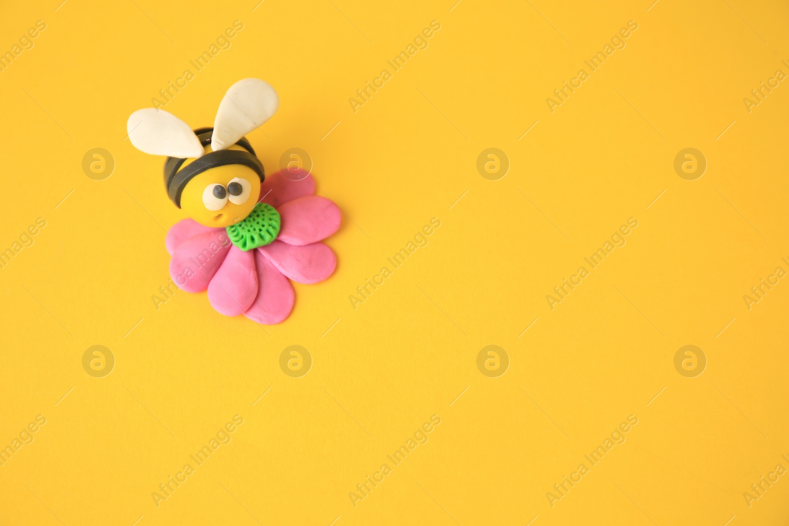 Photo of Bee with flower made from plasticine on orange background, space for text. Children's handmade ideas