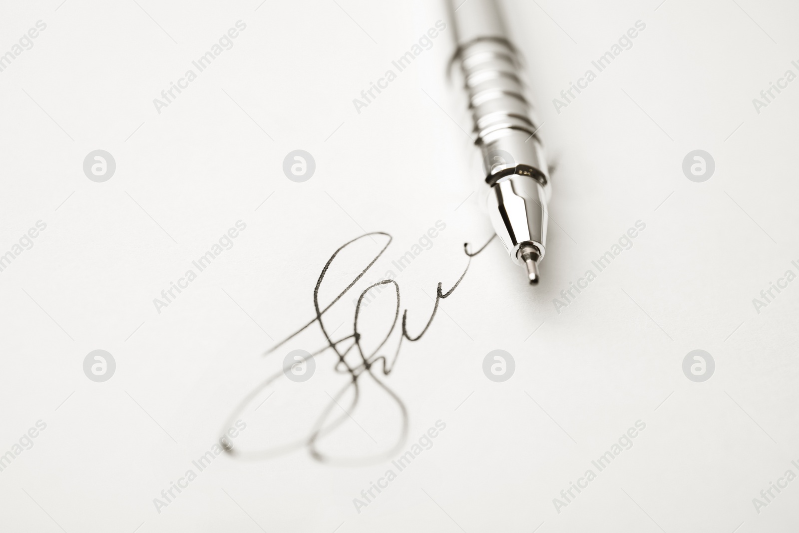 Photo of Modern pen and signature on sheet of white paper, closeup