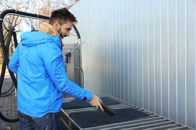 Man cleaning auto carpets with vacuum cleaner at self-service car wash