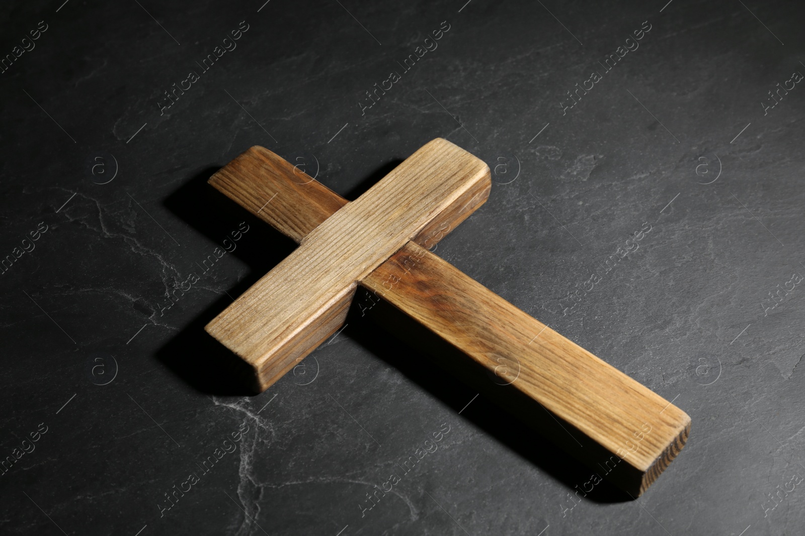 Photo of Wooden Christian cross on black slate table. Religion concept