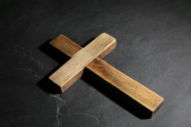 Photo of Wooden Christian cross on black slate table. Religion concept