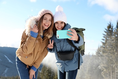 Friends taking selfie in mountains during winter vacation