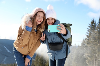 Photo of Friends taking selfie in mountains during winter vacation