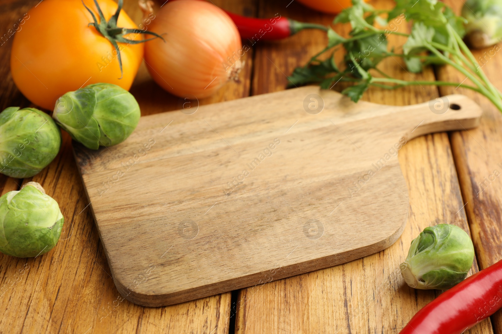 Photo of Empty cutting board and different vegetables on wooden table