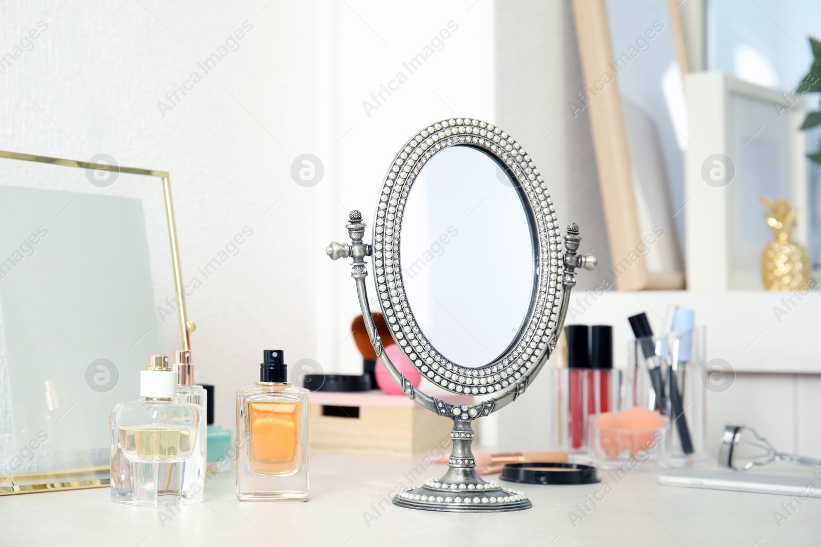 Photo of Mirror in antique frame and different cosmetics on dressing table. Beauty blogger