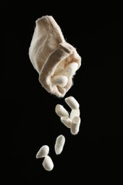 Photo of Shaking white silk cocoons out of sackcloth bag on black background