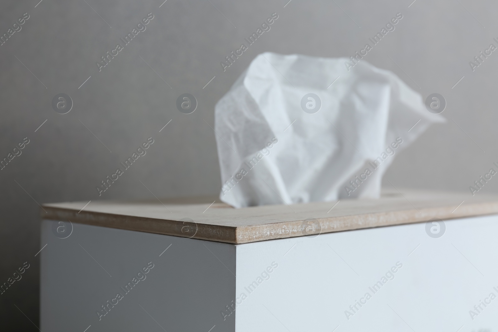 Photo of Holder with paper tissues on grey background, closeup