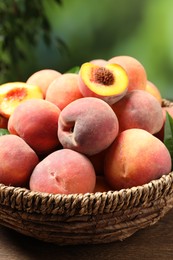 Photo of Cut and whole fresh ripe peaches in basket on wooden table against blurred background, closeup