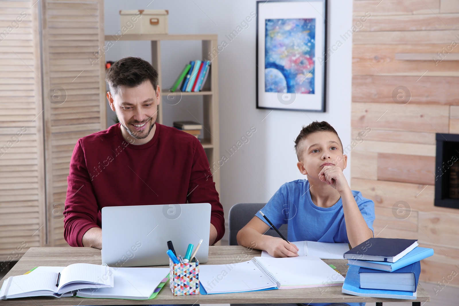 Photo of Dad helping his son with homework in room