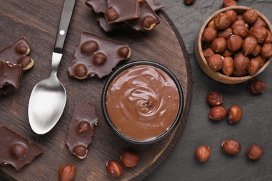 Bowl with tasty paste, chocolate pieces and nuts on grey table, flat lay
