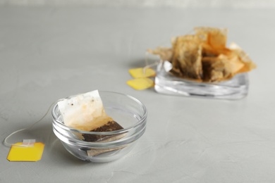 Photo of Glass bowl with used tea bag on grey table