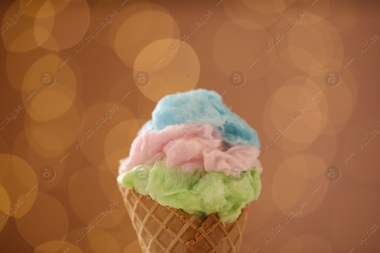 Photo of Sweet cotton candy in waffle cone against blurred lights, closeup