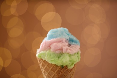 Sweet cotton candy in waffle cone against blurred lights, closeup