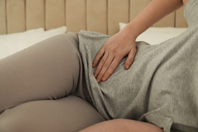 Woman suffering from appendicitis inflammation at home, closeup