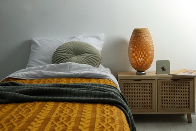 Stylish lamp, magazine and alarm clock on bedside table indoors. Bedroom interior elements