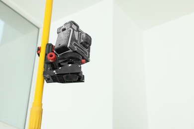 Modern cross line laser level indoors, space for text. Tiles installation process