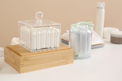 Photo of Many different tampons and personal care products on white table near beige wall