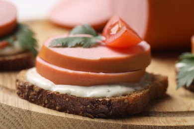 Photo of Delicious sandwich with boiled sausage, tomato and sauce on board, closeup
