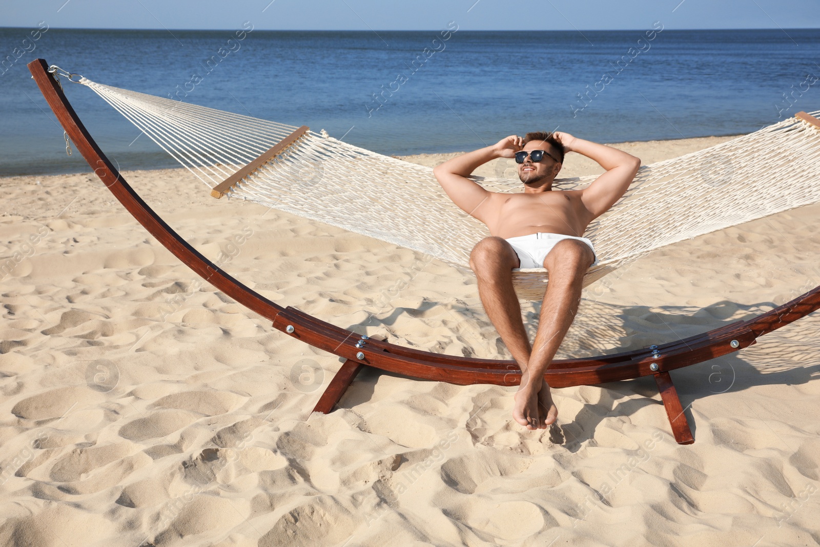 Photo of Young man relaxing in hammock on beach