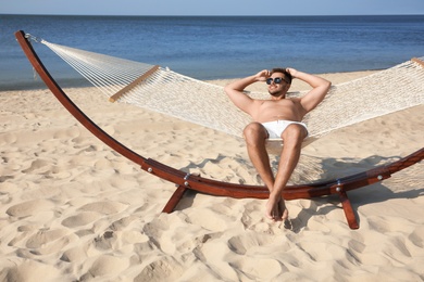 Photo of Young man relaxing in hammock on beach