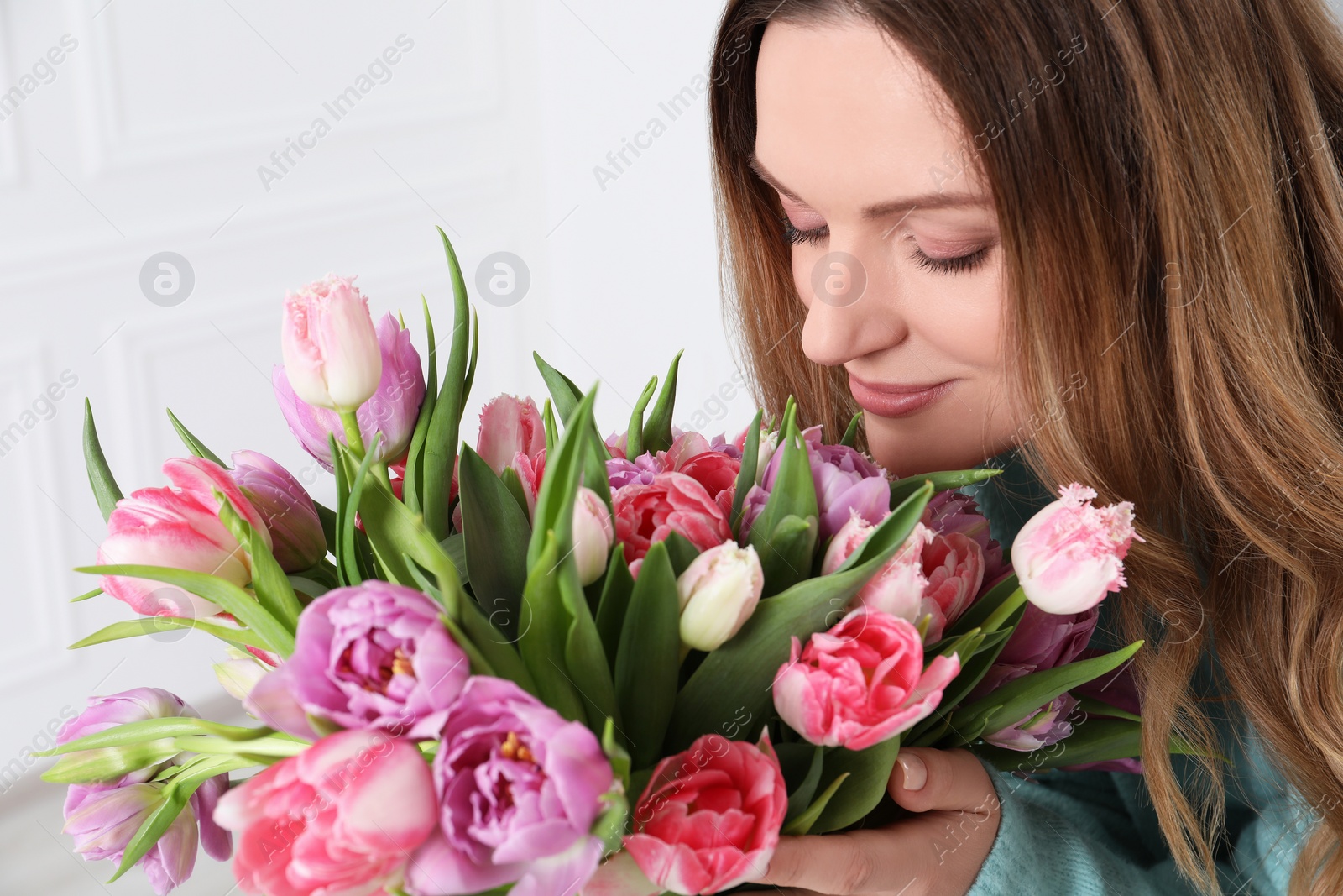 Photo of Young woman with bouquet of beautiful tulips indoors, closeup