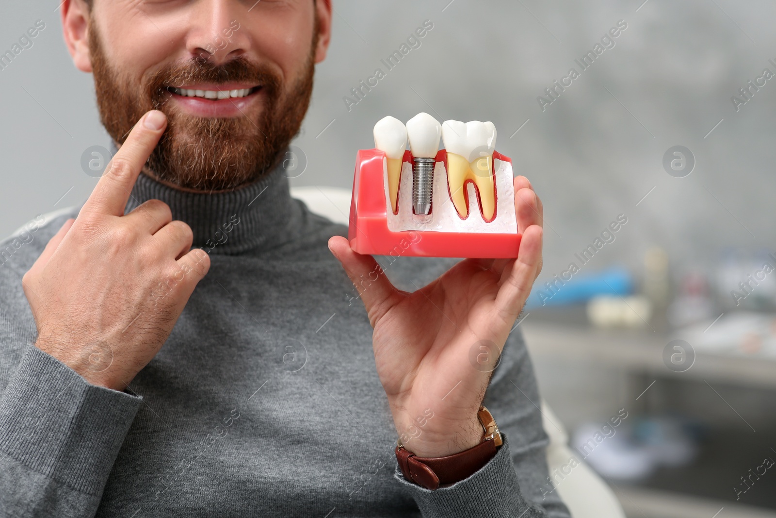Photo of Man holding educational model of dental implant on blurred background, closeup. Space for text